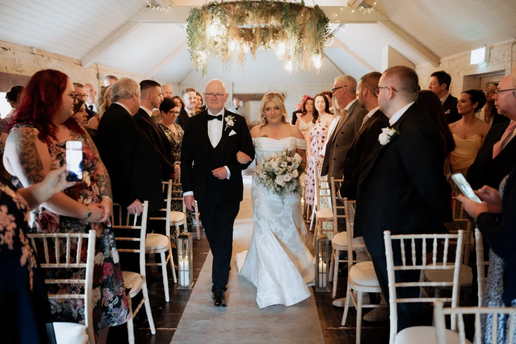 Emma walking down the aisle in the Coach House during her wedding in Northern Ireland.
